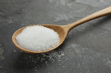 Gri desenli masada granüle şekerli kaşık, yakın plan.