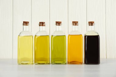 Sebze yağları. Beyaz ahşap masada cam şişelerde farklı pişirme yağları.