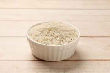 Beyaz ahşap masada, kasede çiğ basmati pilavı, yakın plan.