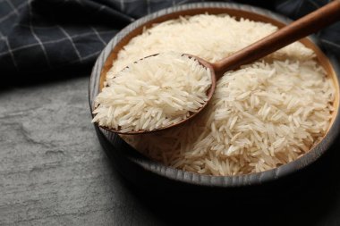 Tabakta çiğ basmati pilavı ve siyah masada kaşık, yakın plan.