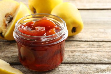 Kavanozda ev yapımı ayva reçeli ve ahşap masada meyveler, yakın plan. Metin için boşluk