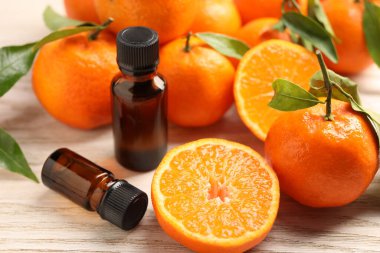 Mandalina yağı şişeleri ve ahşap masada taze meyveler.