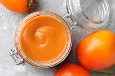 Lezzetli hurma reçeli ve gri masada taze meyveler.