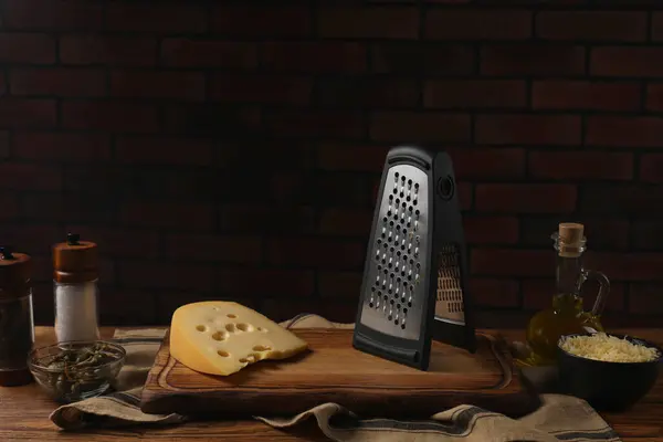 Cheese, grater and spices on wooden table