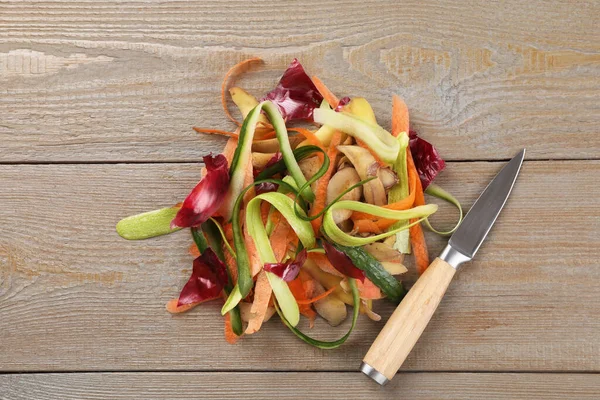木のテーブルの新鮮な野菜とナイフの皮 トップビュー — ストック写真