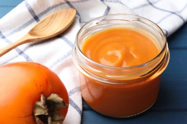 Cam kavanozdaki leziz hurma reçeli mavi ahşap masada servis edilir, yakın plan.