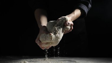 Ekmek yapıyorum. Masada hamur yoğuran kadın, yakın plan.