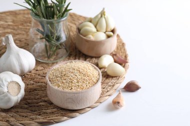 Kasede kurutulmuş sarımsak taneleri, biberiye ve beyaz masada taze karanfil. Metin için boşluk