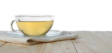 Beyaz arka planda, tahta masada fincanda yeşil çay tazeleniyor.