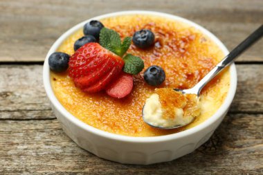 Lezzetli creme brulee kasede böğürtlen ve tahta masada kaşık, yakın plan