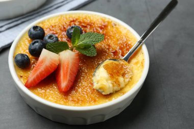Lezzetli creme brulee kasede böğürtlen ve gri masada kaşık, yakın plan