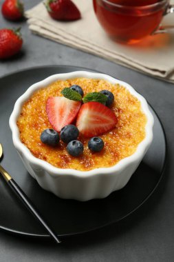 Böğürtlenli nefis creme brulee ve gri masadaki nane şekeri, yakın plan