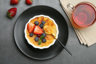 Böğürtlenli ve nane şekerli leziz creme brulee gri masada servis edilir.