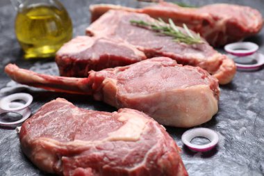 Gri desenli masada taze çiğ et ve soğan halkaları, yakın plan.