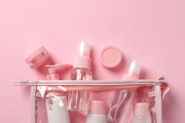 Pembe arka planda kozmetik seyahat seti olan plastik torba, düz. Banyo aksesuarları