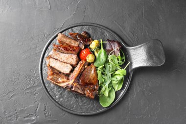 Lezzetli ızgara et, sebze ve sebzeler siyah masada.