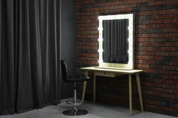 Mirror with light bulbs, table, chair and curtain in makeup room
