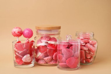 Bej arka planda cam kavanozlarda lezzetli pembe şekerler.