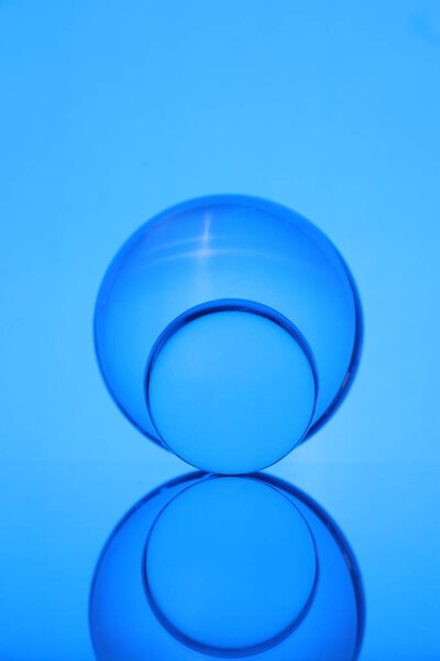 Transparent glass balls on mirror surface against blue background