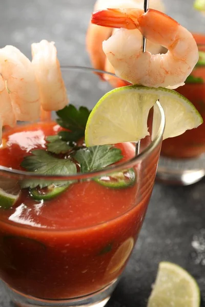 Tasty shrimp cocktail with sauce in glass and lime on grey table, closeup