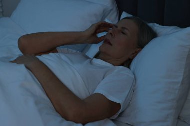 Geceleri yatakta baş ağrısı çeken bir kadın