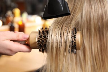 Kuaför kuaför kuaförde müşterinin saçını kurutuyor.