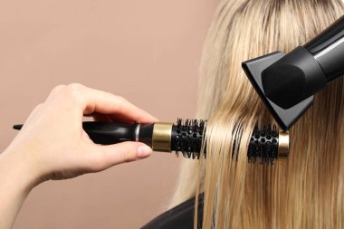 Kuaför bej arka planda müşterinin saçını kurutuyor, yakın plan.