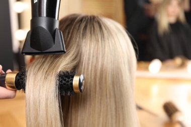 Kuaför kuaför kuaförde müşterinin saçını kurutuyor.