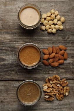 Kavanozlarda lezzetli fındık ezmesi ve ahşap masada çiğ fındık.