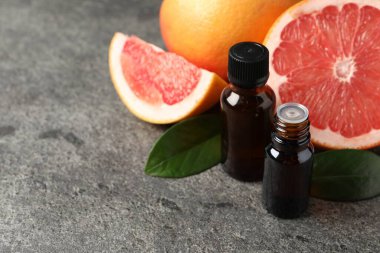 Şişelerde greyfurt yağı, koyu dokulu masada yapraklar ve meyveler, yakın çekim. Metin için boşluk