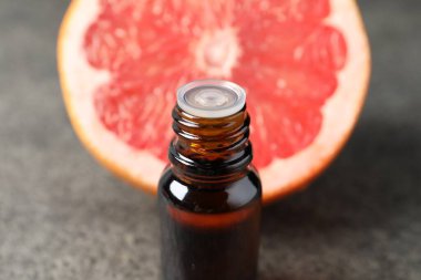 Şişede greyfurt yağı ve karanlık masada meyve, yakın plan.