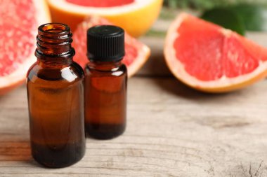 Şişelerde greyfurt yağı ve ahşap masada meyveler, yakın çekim. Metin için boşluk