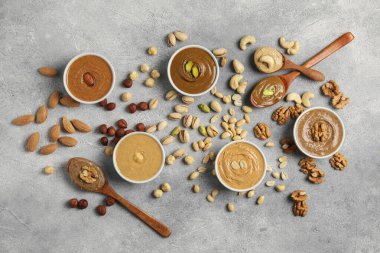 Lezzetli fındık ezmesi ve çiğ fındık açık gri masada, düz yatıyordu.