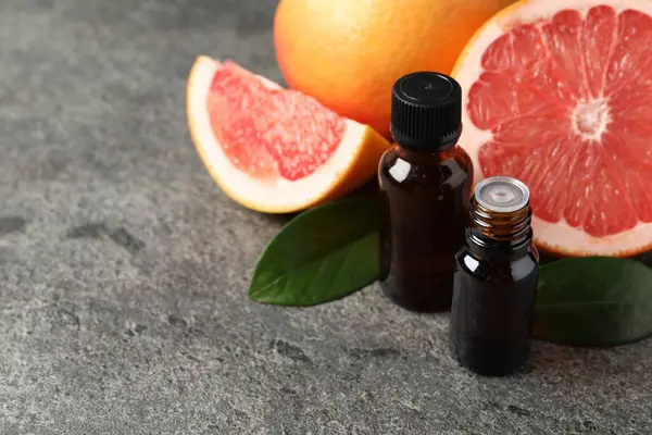 Şişelerde greyfurt yağı, koyu dokulu masada yapraklar ve meyveler, yakın çekim. Metin için boşluk