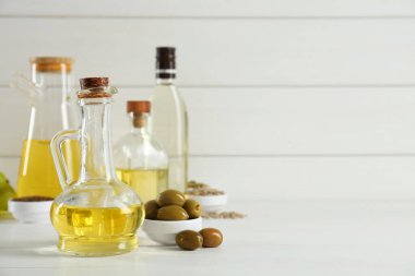 Sebze yağları. Şişelerde farklı pişirme yağları ve beyaz ahşap masada malzemeler, metin için yer.