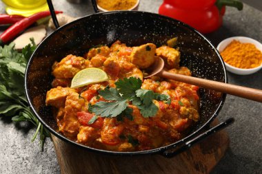 Lezzetli körili tavuk ve gri masadaki malzemeler.