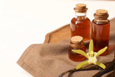 Aromatik vanilya özü, kapsüller ve çiçekler beyaz masada, yakın plan. Metin için boşluk