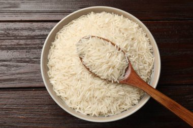 Çiğ basmati pilavı ve kaşıkla ahşap masa, üst manzara.