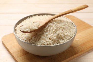 Çiğ basmati pilavı ve beyaz ahşap masada kaşık.