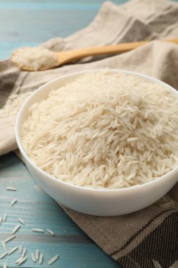 Kase içinde çiğ basmati pilavı açık mavi ahşap masada.