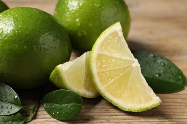 Taze limon ve yeşil yapraklarla ahşap masaya su damlaları, yakın plan.