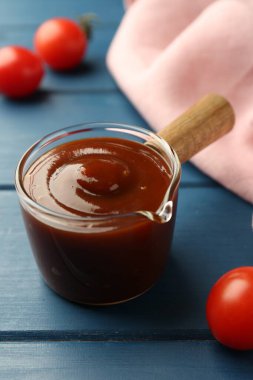 Lezzetli barbekü sosu ve domates mavi ahşap masada, yakın plan.