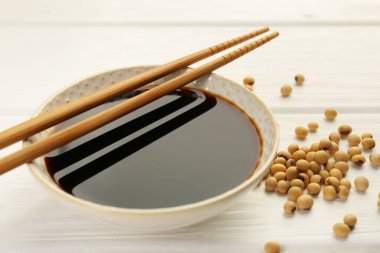 Tabakta soya sosu, yemek çubukları ve soya fasulyesi beyaz ahşap masada, yakın plan.