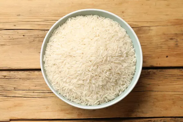 Tabakta çiğ basmati pilavı, ahşap masa, üst manzara.