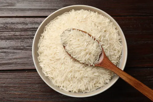 Çiğ basmati pilavı ve kaşıkla ahşap masa, üst manzara.