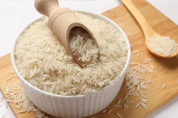 Tabakta çiğ basmati pilavı, beyaz masada kepçe ve kaşık, yakın plan.