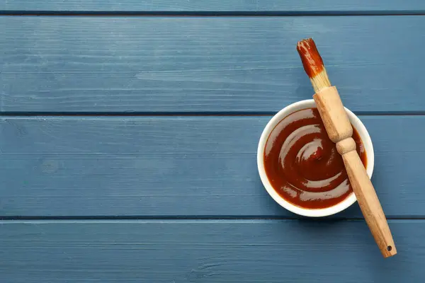 Kasede lezzetli barbekü sosu ve mavi ahşap masada fırça, üst manzara. Metin için boşluk
