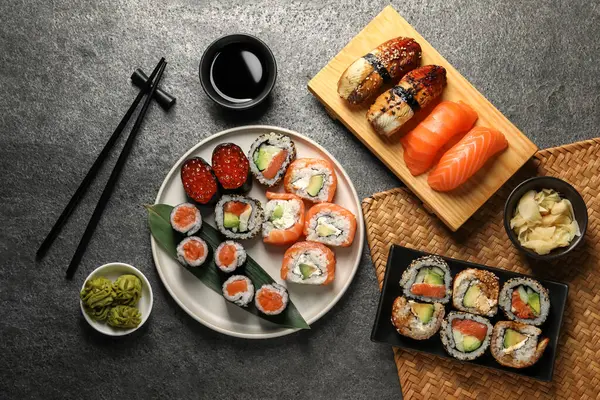 Flat lay composition with delicious sushi rolls on dark grey table