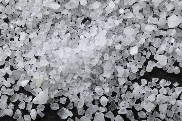 Siyah masaya dağılmış beyaz doğal tuz, üst görünüm.