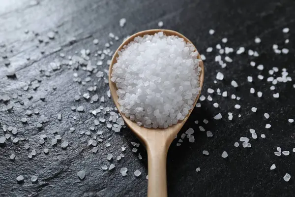 Siyah masada organik beyaz tuz ve kaşık, yakın plan.